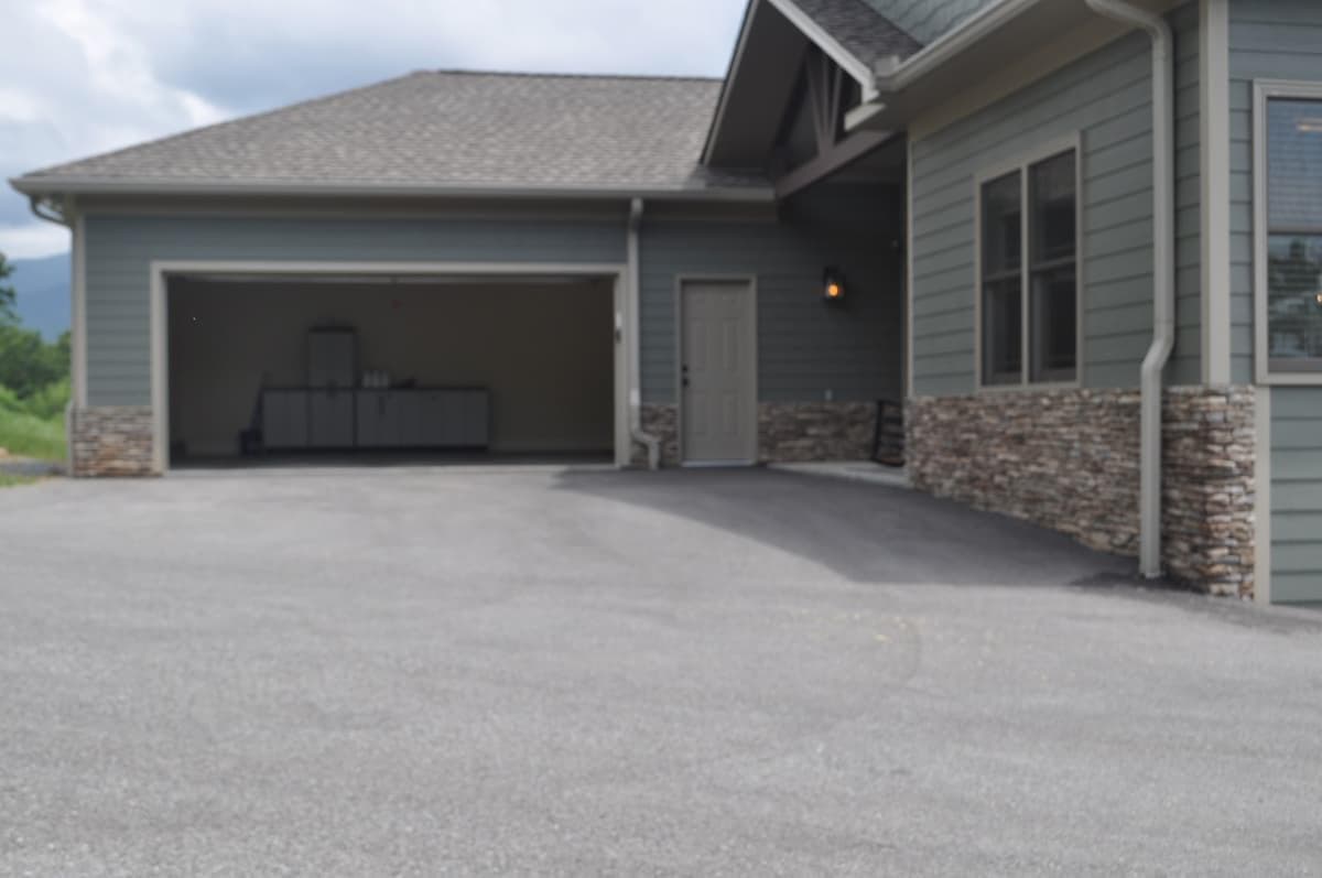 The parking pad is flat and wider than a two car garage.  The parking pad black top is skimmed up to the front porch concrete only leaving a small edge for water retention/drainage.  Wheelchair ramp is located in garage door entryway but can be moved